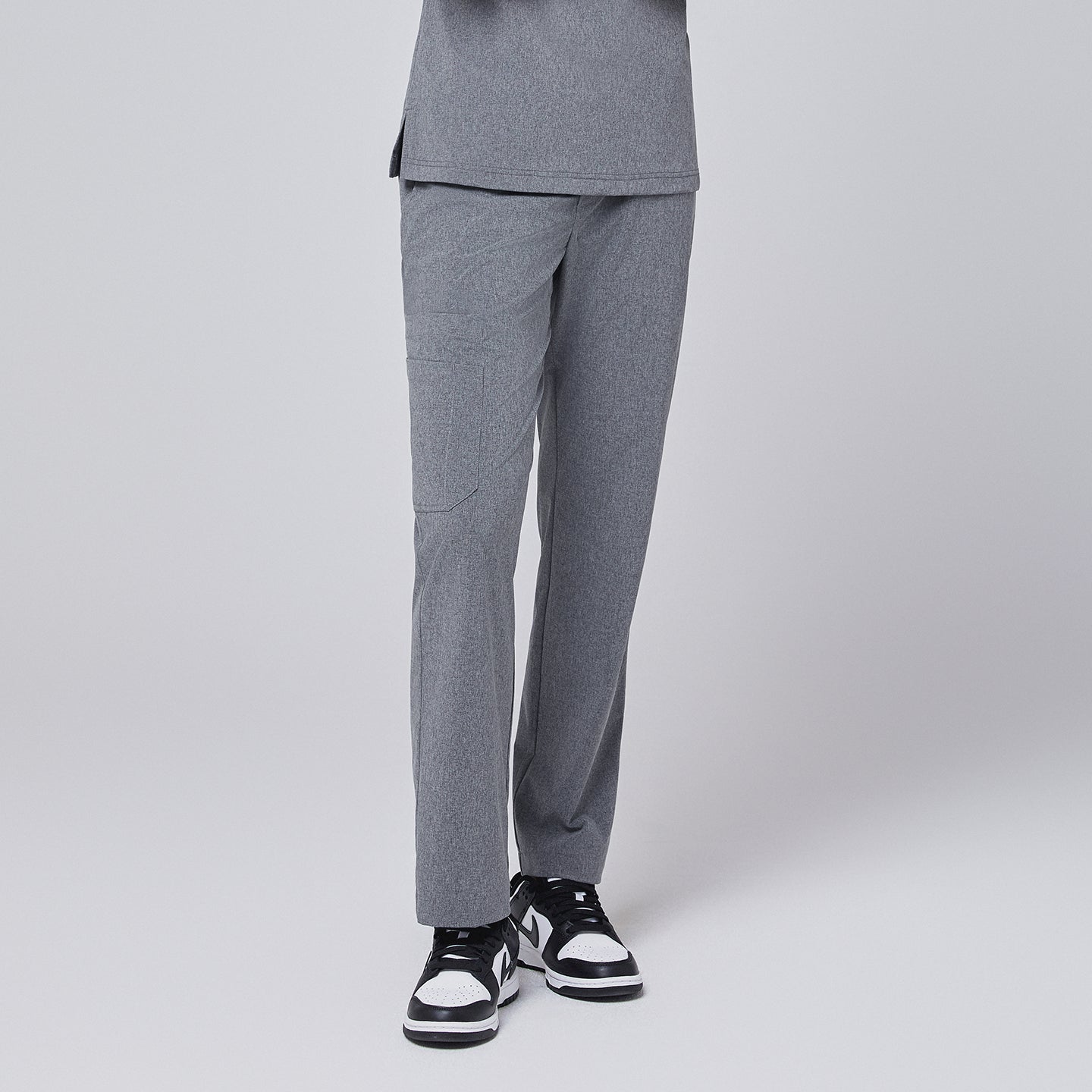 Image of Ash gray straight leg scrub pants with a split hem, featuring a cargo pocket, paired with black-and-white sneakers on a neutral background,Ash Gray
