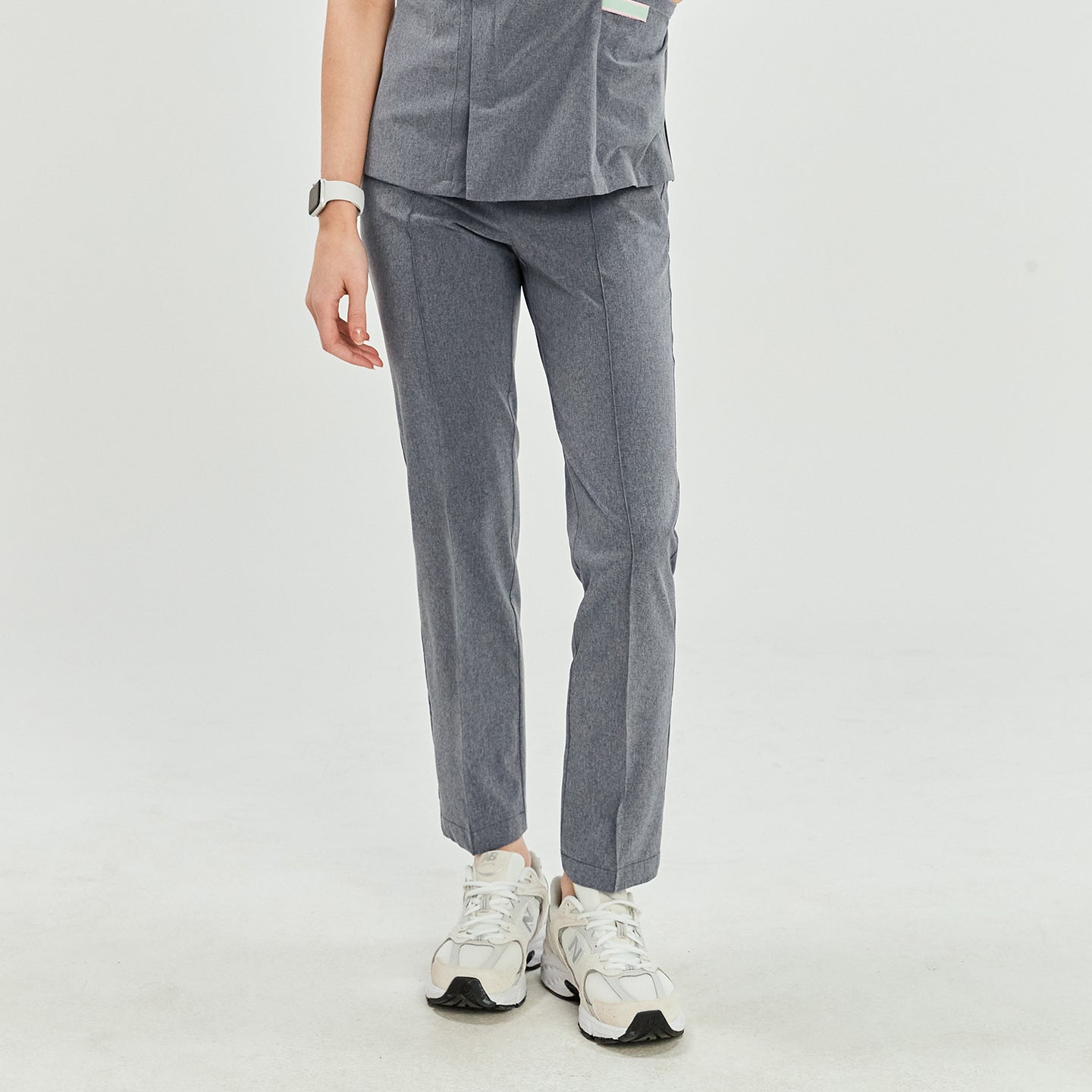 Image of Ash gray scrub pants with straight legs, paired with white sneakers, shown in a standing pose,Ash Gray