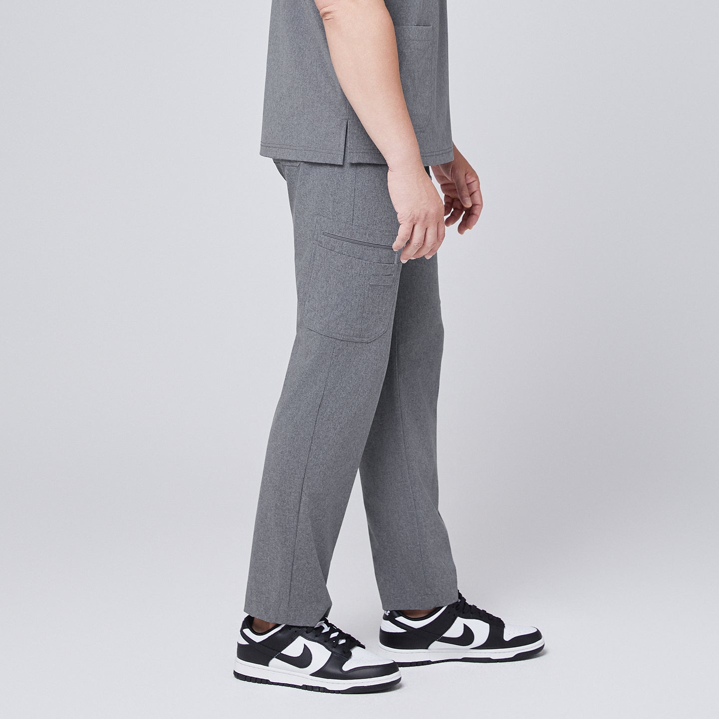Image of Male model wearing ash gray relaxed-fit scrub pants with side pockets, styled with black and white sneakers, showcasing a side angle for a modern and functional look,Ash Gray