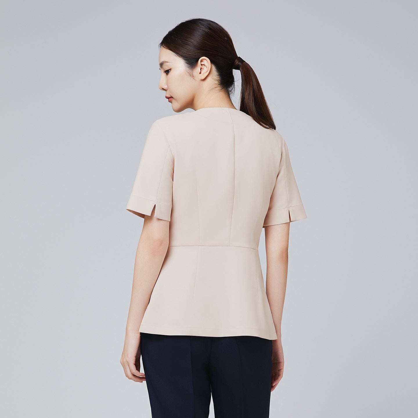 Image of Back view of TUL NS-149 Beige scrub top, showcasing structured paneling and short sleeves for a professional silhouette.