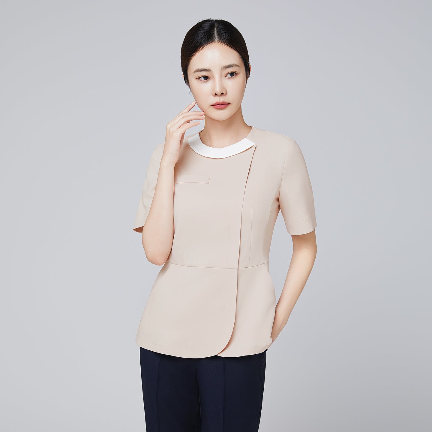 Image of Front angle of TUL NS-149 Beige scrub top with a round white collar, showing a concealed front zipper and sleek short sleeves.