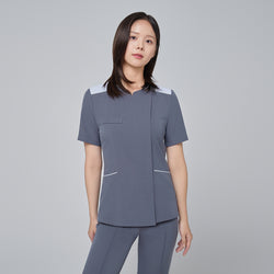 Image of Model wearing TUL OS-202 Women's One Button Front Zipper Scrub Top in Blue Gray, paired with matching scrub bottoms, displaying a cohesive, modern uniform ideal for healthcare settings.