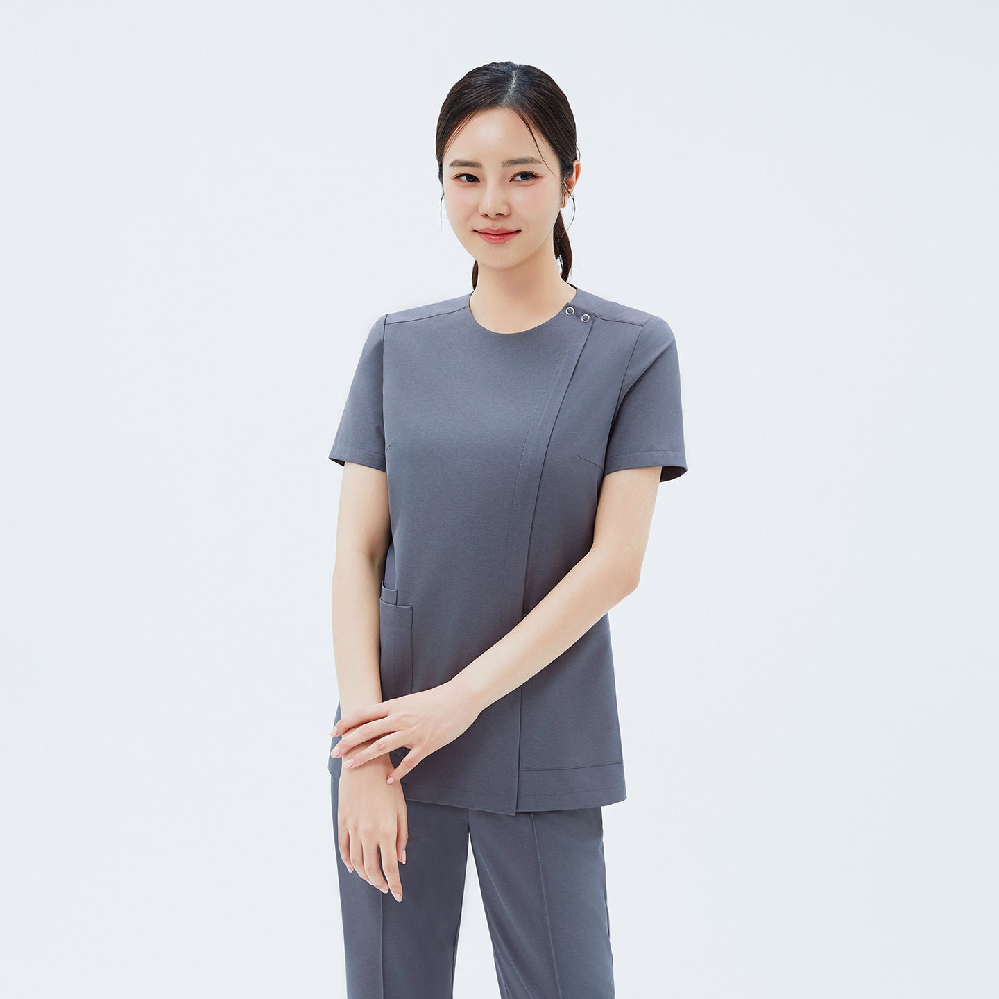 Front view of TUL OS-212 Women's Dual Snap Front Zipper Scrub Top in Blue Gray, highlighting snap details at the shoulder and practical front pockets.