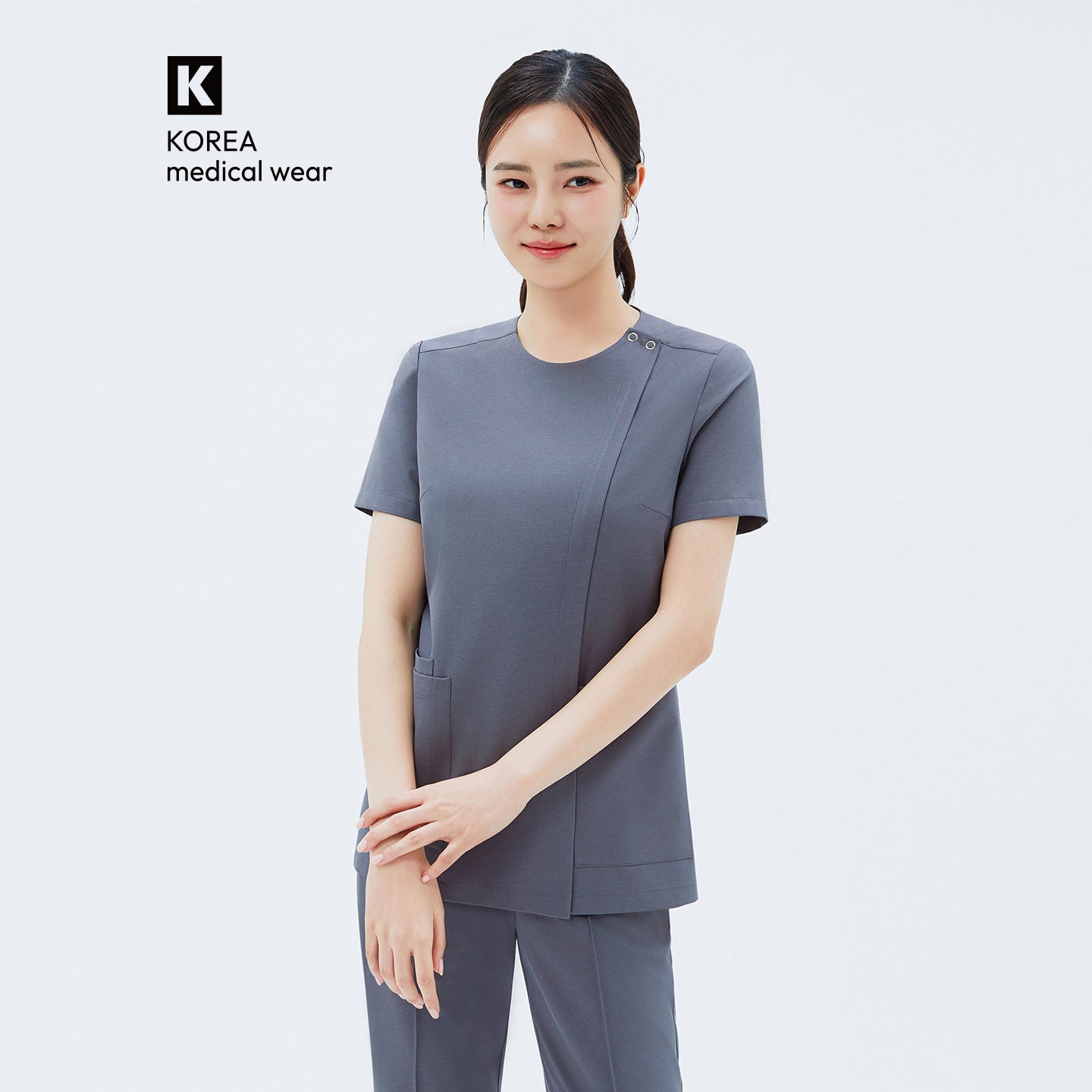 Image of Front view of TUL OS-212 Women's Dual Snap Front Zipper Scrub Top in Blue Gray, highlighting snap details at the shoulder and practical front pockets.