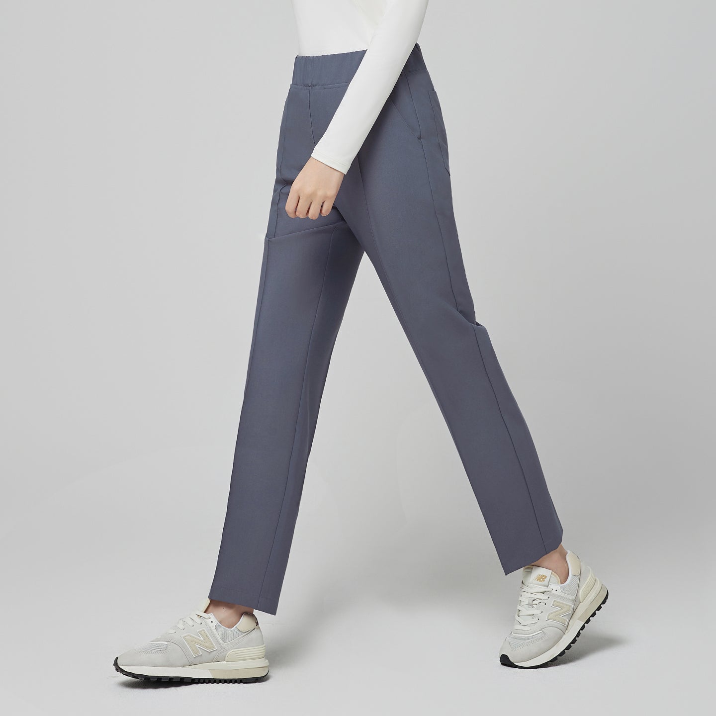 Image of Model wearing TUL Women's Premium Banding Pants in Blue Gray with a pink cardigan, highlighting a modern, comfortable silhouette.