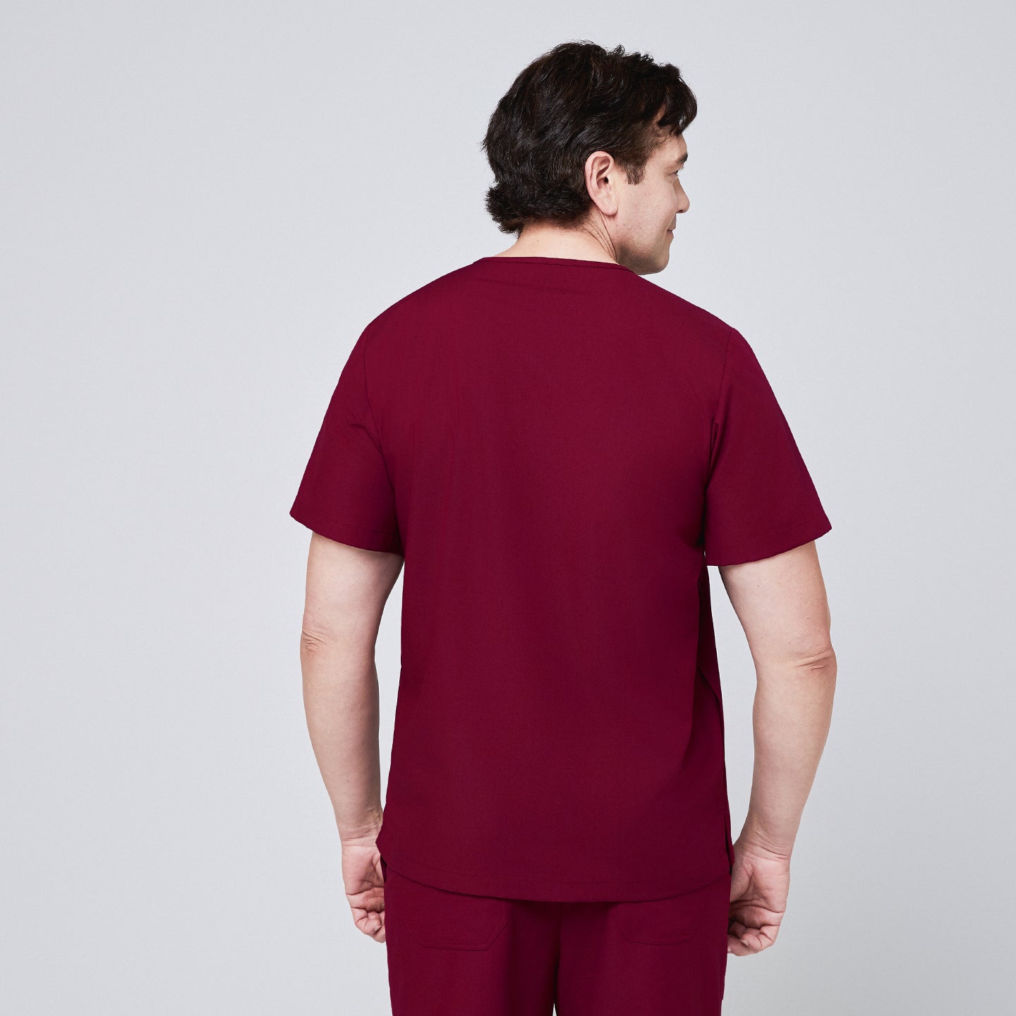 Image of Back view of a man wearing a burgundy scrub top paired with matching scrub pants,Burgundy