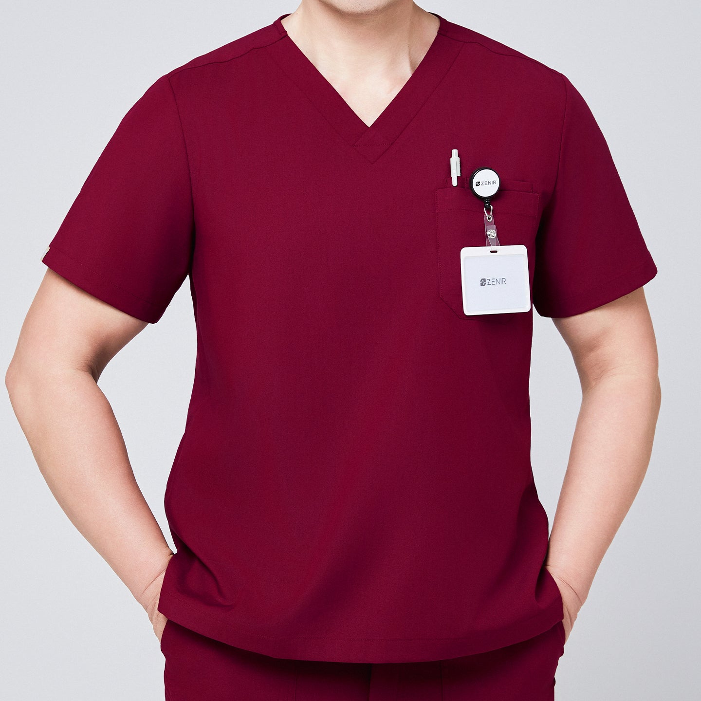 Close-up of a burgundy V-neck scrub top featuring a chest pocket with badge holder and pen, paired with matching scrub pants,Burgundy