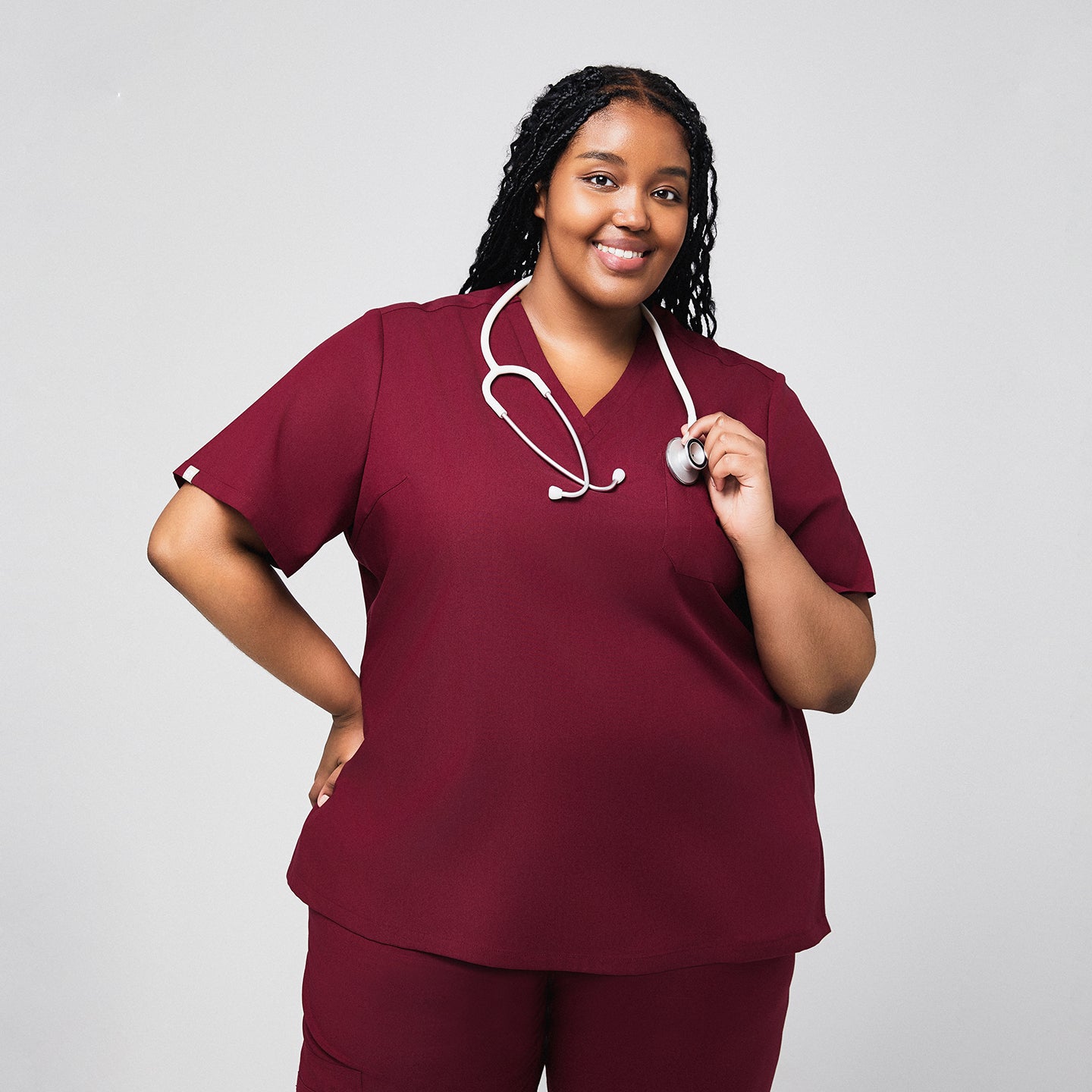 Image of Woman smiling in a burgundy scrub set with a stethoscope draped around her neck,Burgundy