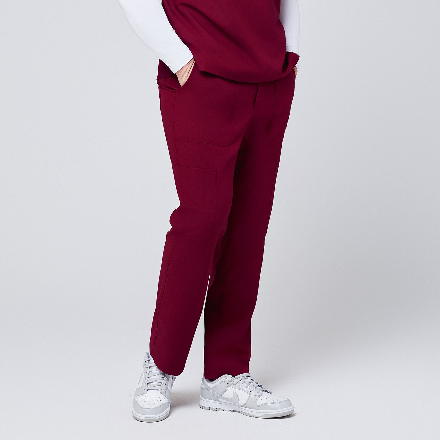 Image of Side view of burgundy 8-pocket straight scrub pants with functional pockets, paired with white sneakers,Burgundy