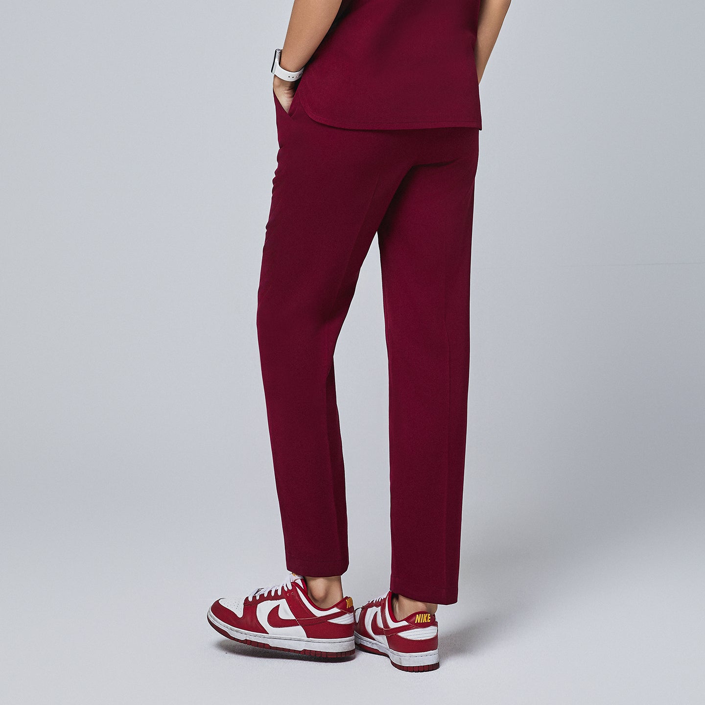 Image of Back view of burgundy straight-leg scrub pants with rear pockets, paired with red and white sneakers, showcasing a tailored fit,Burgundy