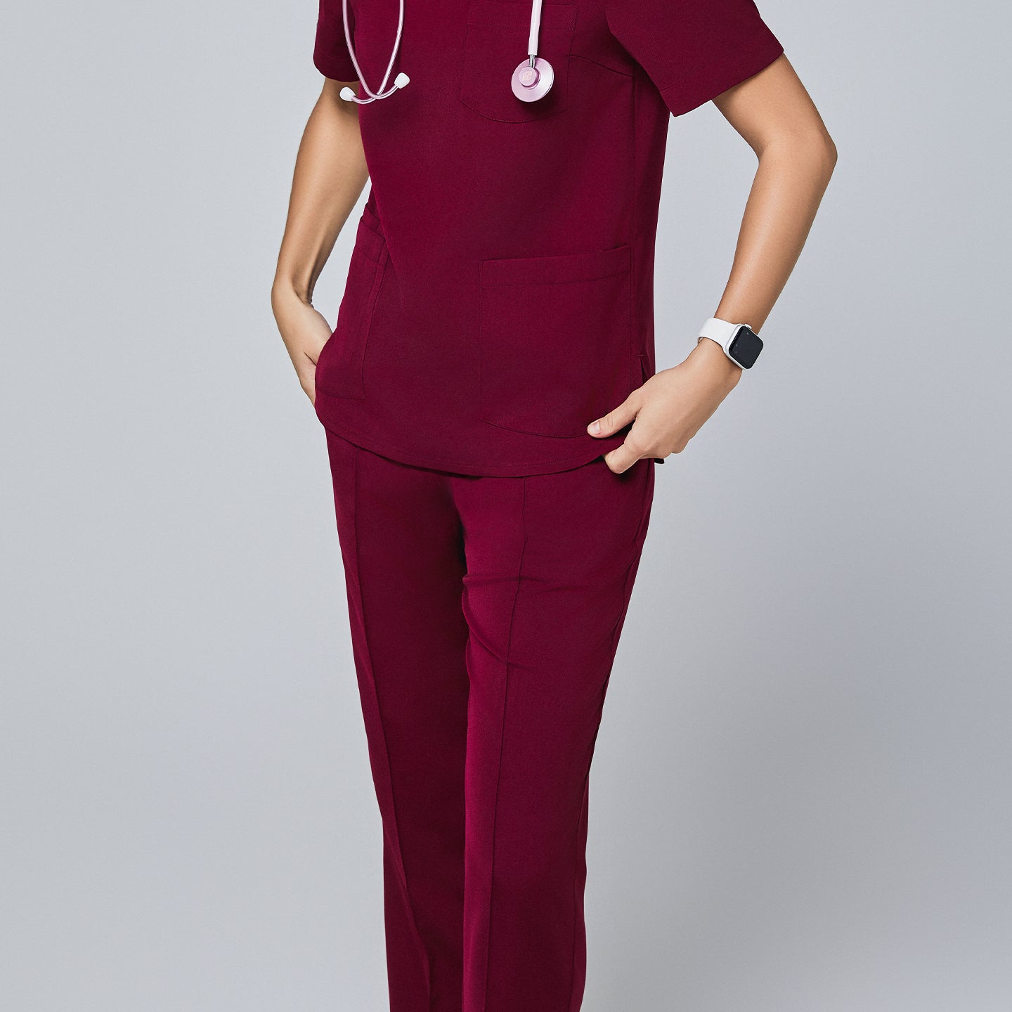 Close-up of a woman wearing a burgundy scrub set with straight-leg pants, pockets, and a stethoscope, accessorized with a smartwatch,Burgundy