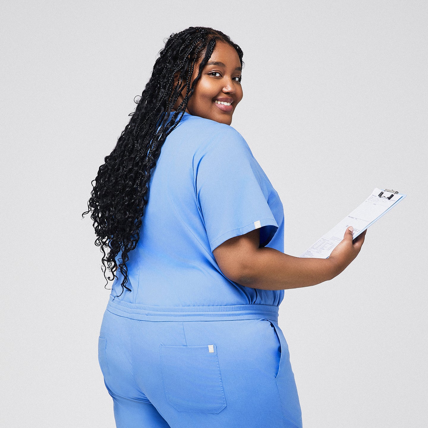 Image of Plus-size model wearing a celi blue 3-pocket scrub top, holding a clipboard and smiling, ideal for healthcare professionals,Ceil Blue