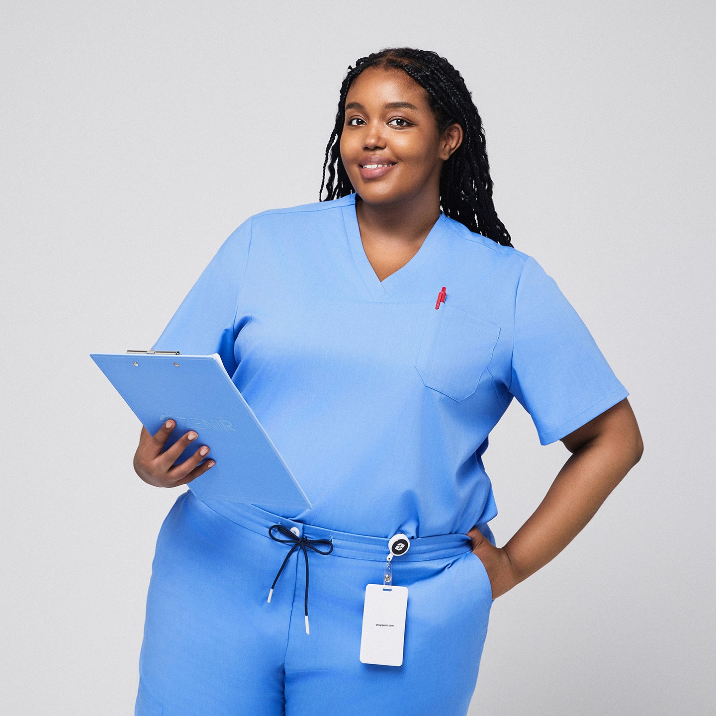 Image of Plus-size model wearing a light blue 3-pocket scrub top, holding a clipboard with badge holder attached, ideal for medical professionals,Ceil Blue