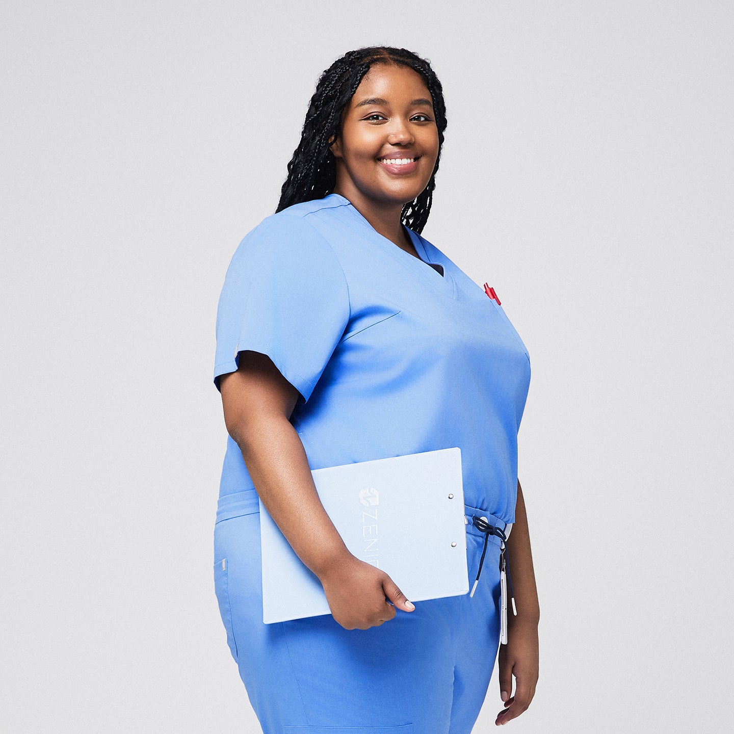 Image of Plus-size model in light blue 3-pocket scrub top, holding a clipboard, showcasing a professional and comfortable healthcare uniform,Ceil Blue