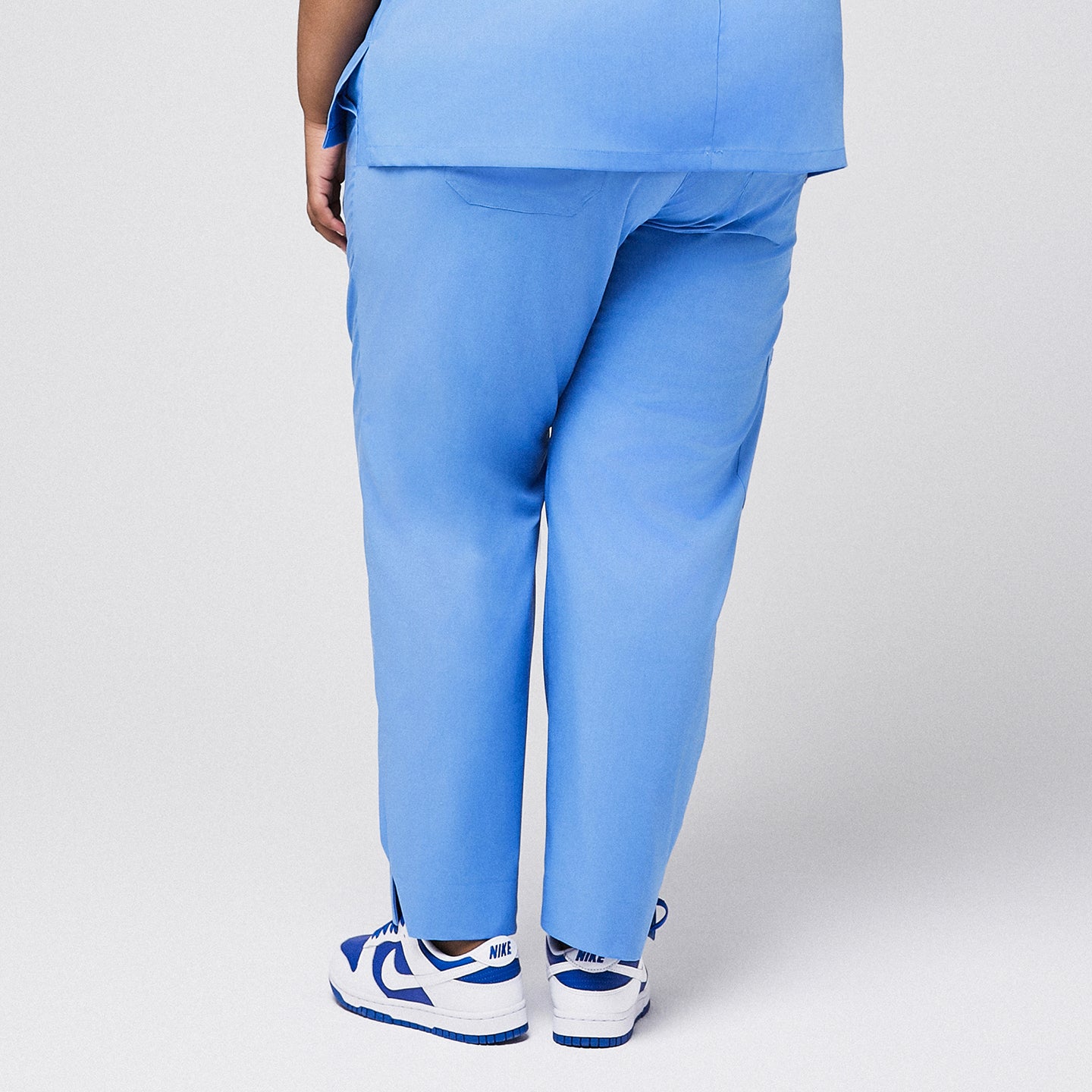 Image of Back view of blue scrub pants with split hem, paired with blue sneakers,Ceil Blue