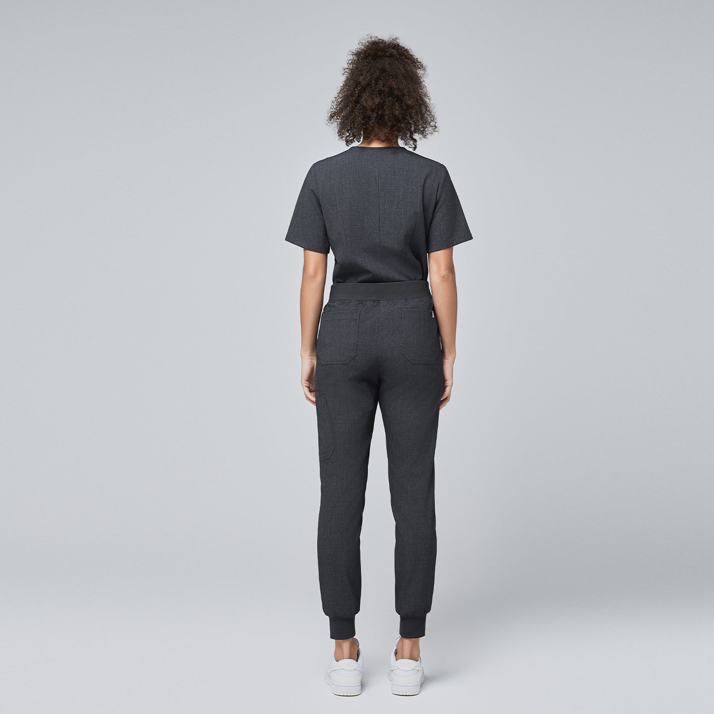 Image of Back view of a model wearing Zenir charcoal gray scrub set with jogger-style pants,Charcoal Gray