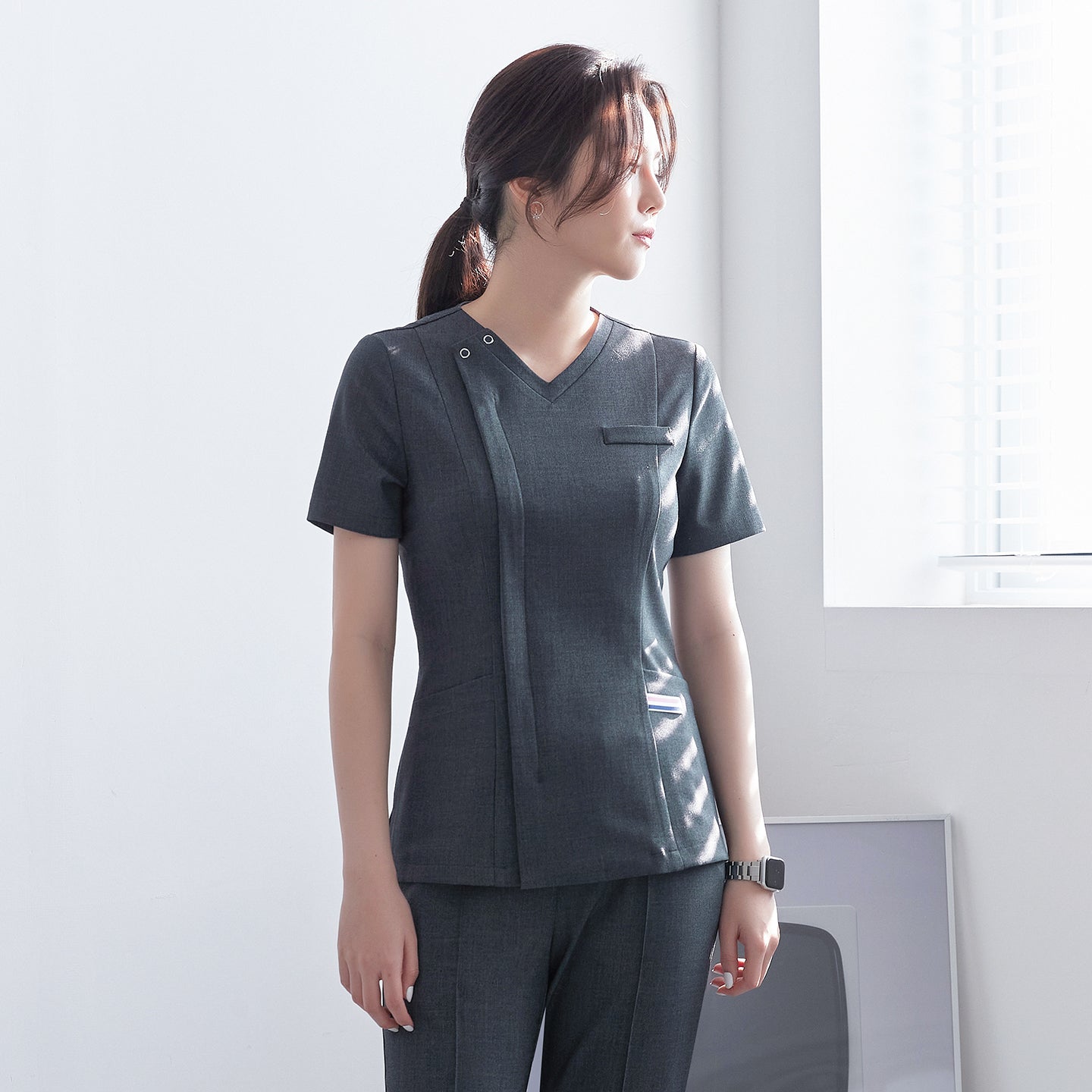 Front view of TUL OS-182 Charcoal Gray scrub top, featuring a V-neckline and snap button detail on the shoulder.