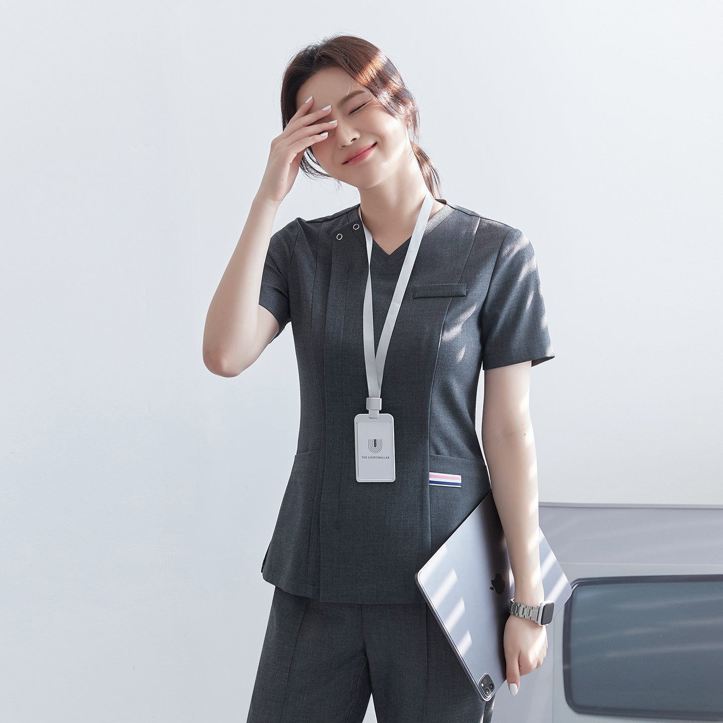 Image of Model wearing TUL OS-182 Charcoal Gray scrub top, highlighting the front zipper closure and chest pocket.