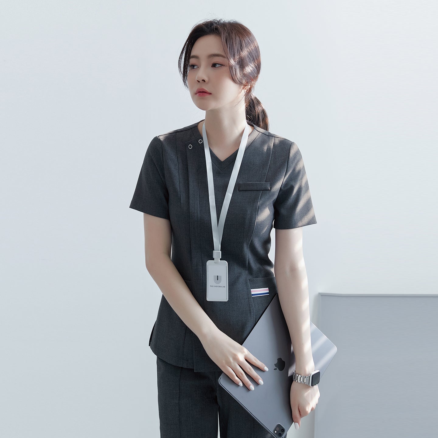 Image of Close-up of TUL OS-182 Women's scrub top in Charcoal Gray, with a V-neck design, front zipper, and short sleeves.