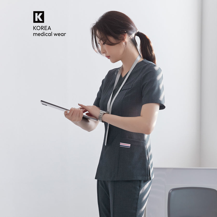 Side view of TUL OS-182 Women's Front Zipper Scrub Top in Charcoal Gray, worn by a model holding a tablet.