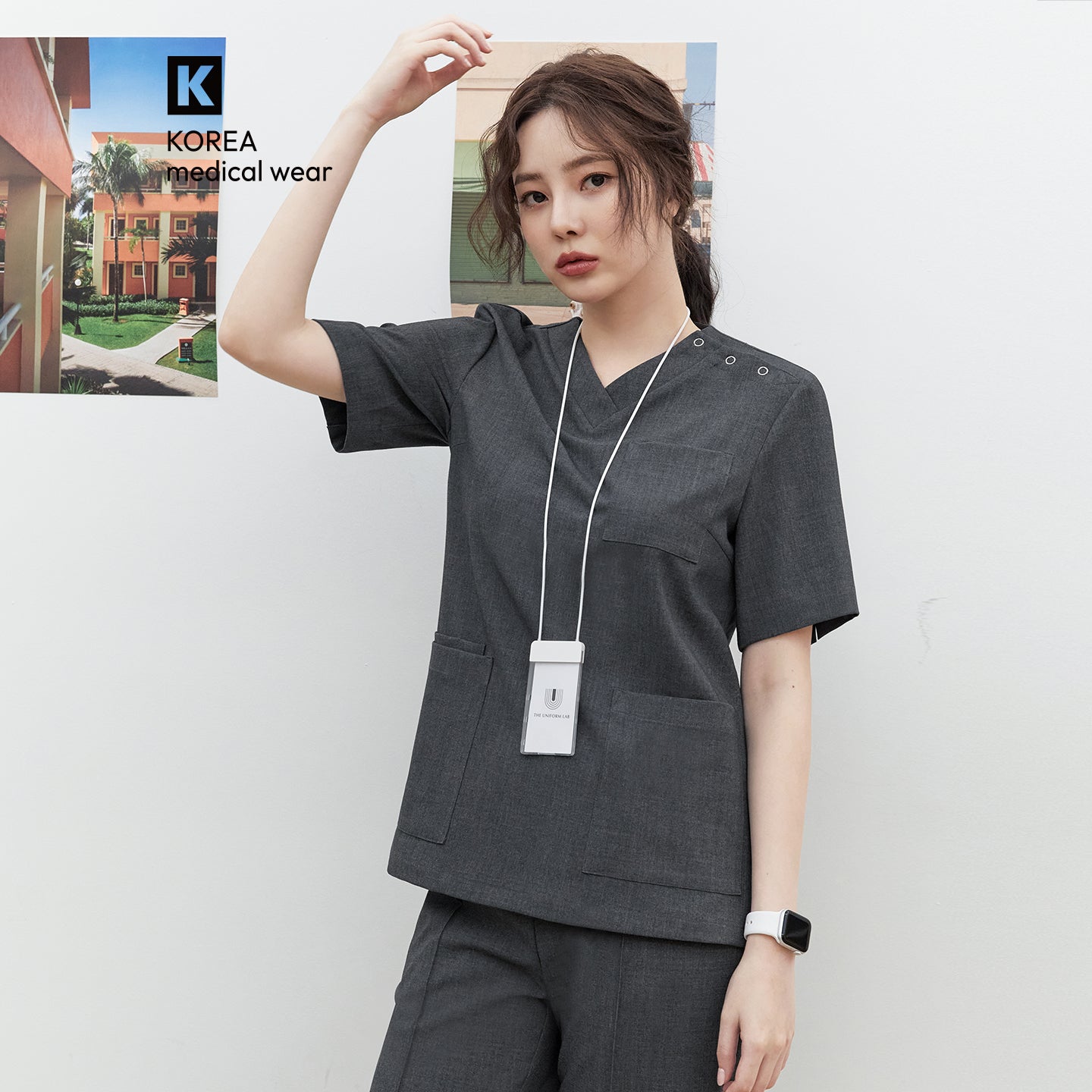 Image of Model wearing TUL OS-186 Women's Snap Button Scrub Top in Charcoal Gray, featuring a V-neck and multiple front pockets.