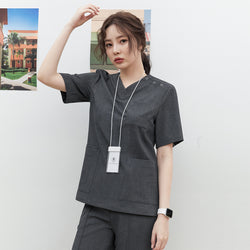 Image of Model wearing TUL OS-186 Women's Snap Button Scrub Top in Charcoal Gray, featuring a V-neck and multiple front pockets.