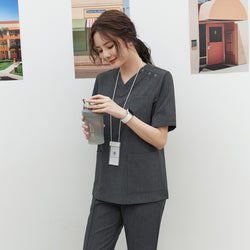 Image of Model in TUL OS-186 Women's Charcoal Gray scrub top, showing snap button closures near the shoulder and large front pockets.