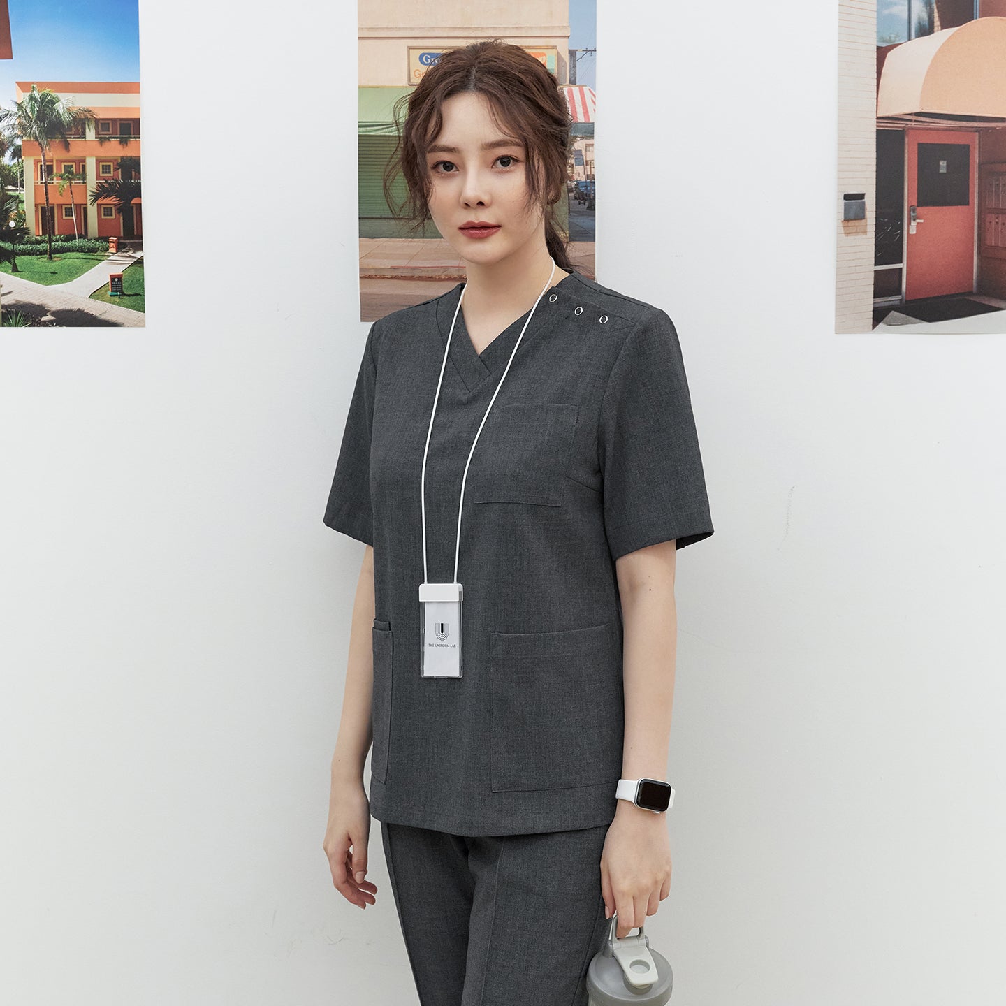 Front shot of TUL OS-186 Charcoal Gray scrub top with a V-neck design, worn by a model holding a water bottle.