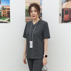 Image of Front shot of TUL OS-186 Charcoal Gray scrub top with a V-neck design, worn by a model holding a water bottle.