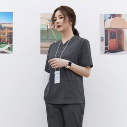Image of Model wearing TUL OS-186 Charcoal Gray scrub top, featuring snap button details near the collar and a relaxed, professional fit.