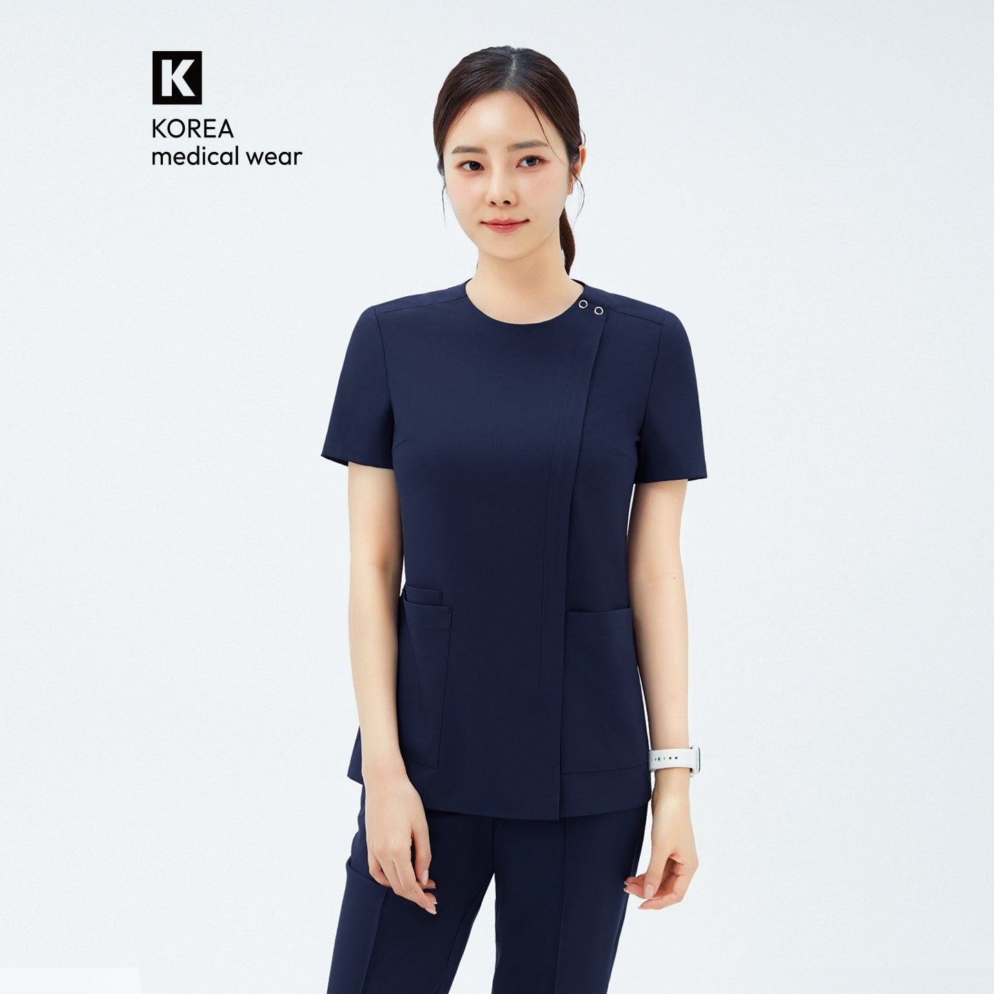 Image of Model wearing TUL OS-213 Women's Dual Snap Front Zipper Scrub Top in Classic Navy, showing snap button detail at the neckline and front pockets.