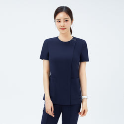 Image of Model wearing TUL OS-213 Women's Dual Snap Front Zipper Scrub Top in Classic Navy, showing snap button detail at the neckline and front pockets.