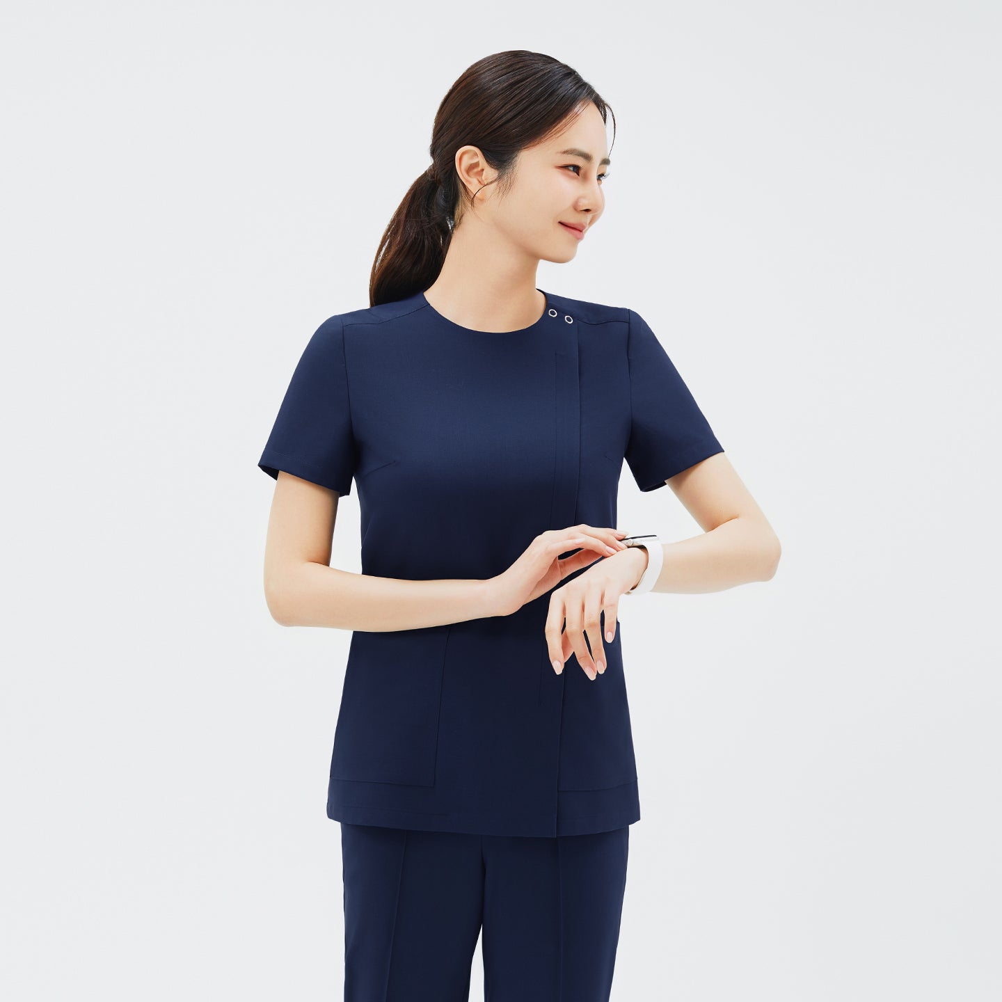 Image of Model wearing TUL OS-213 in Classic Navy, checking a watch, highlighting the dual snap neckline and practical design.