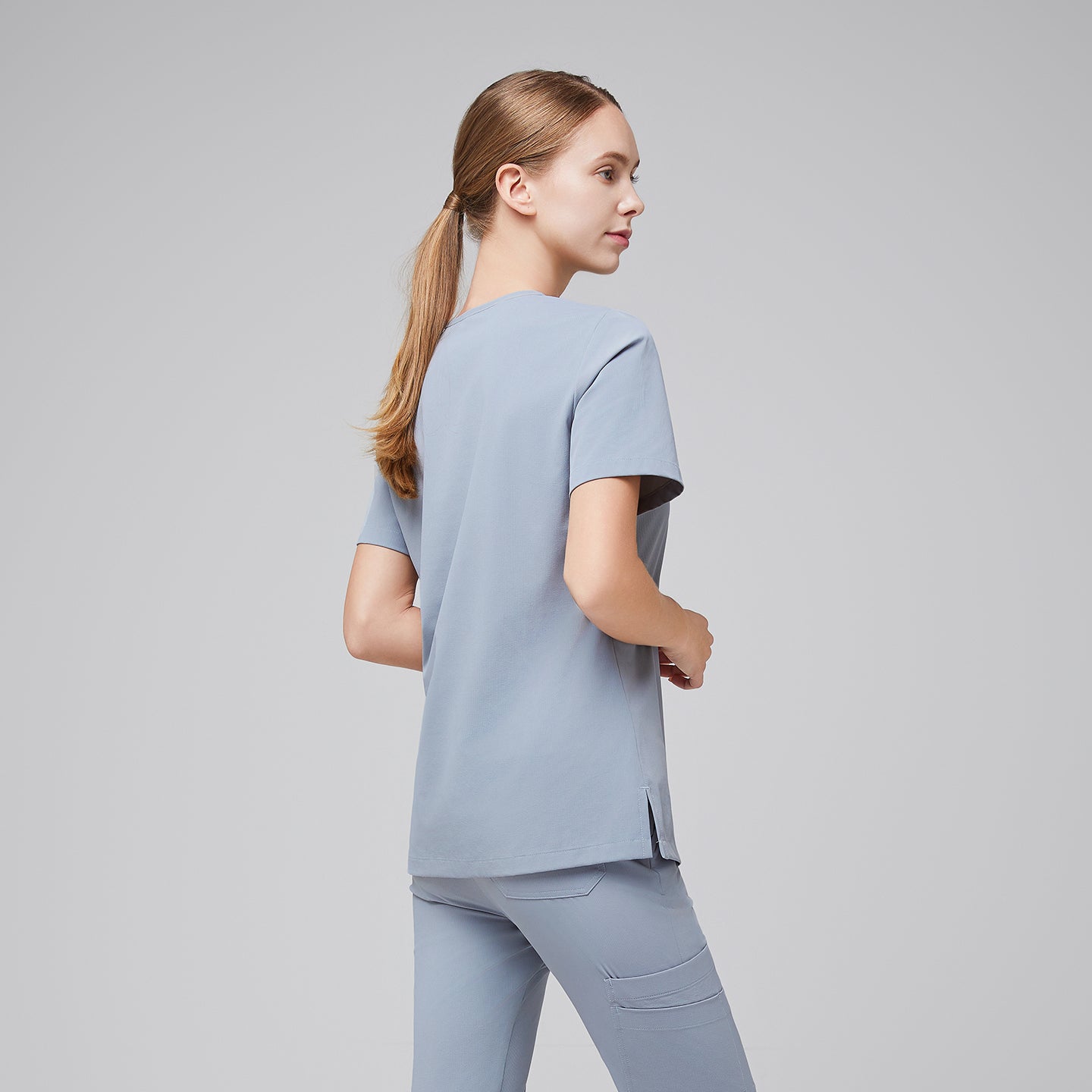 Image of Side-back view of a female healthcare professional in a cool gray scrub set, showing the clean design and relaxed fit,Cool Gray