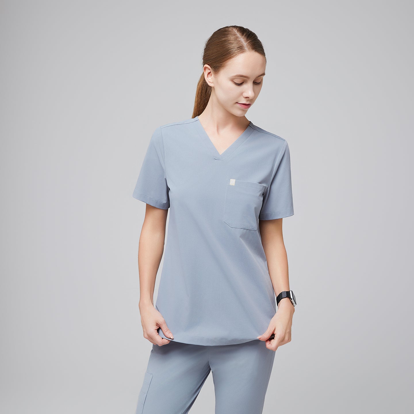 Female healthcare professional wearing a cool gray scrub set with a single pocket, standing in a relaxed pose,Cool Gray