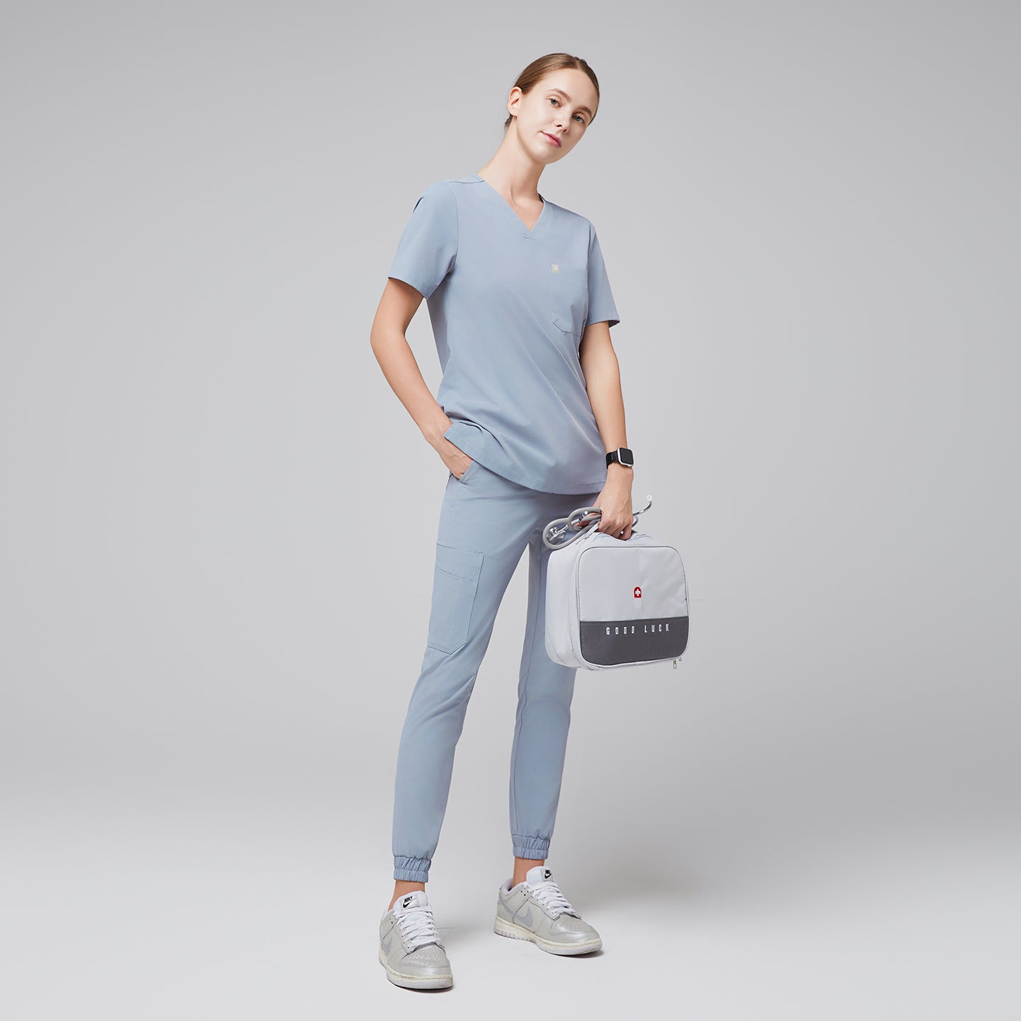 Image of Cool gray single-pocket scrub top Zenir, model wearing with V-neck and relaxed fit, full-body shot.