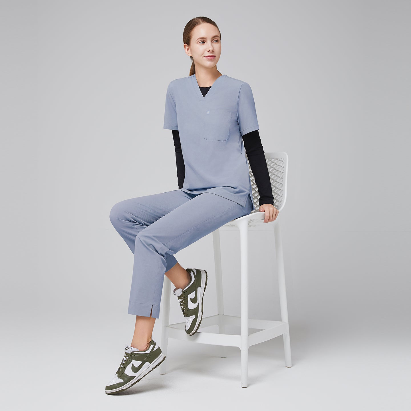 Image of Model seated, wearing cool gray scrubs with black long-sleeve undershirt and green sneakers,Cool Gray