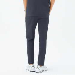 Image of Back angle of TUL Men’s Premium Banding Pants in Deep Gray, showing the model’s left pocket and center back seam. The matching scrub top aligns at the waist, and the model wears white sneakers.