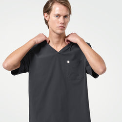 Image of Adjusting the neckline of his scrub top, the male model wears a Deep Gray scrub set, presenting a modern and professional look.