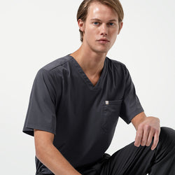Image of Seated in a relaxed pose, the male model wears a Deep Gray scrub set, giving a clean and composed professional appearance.