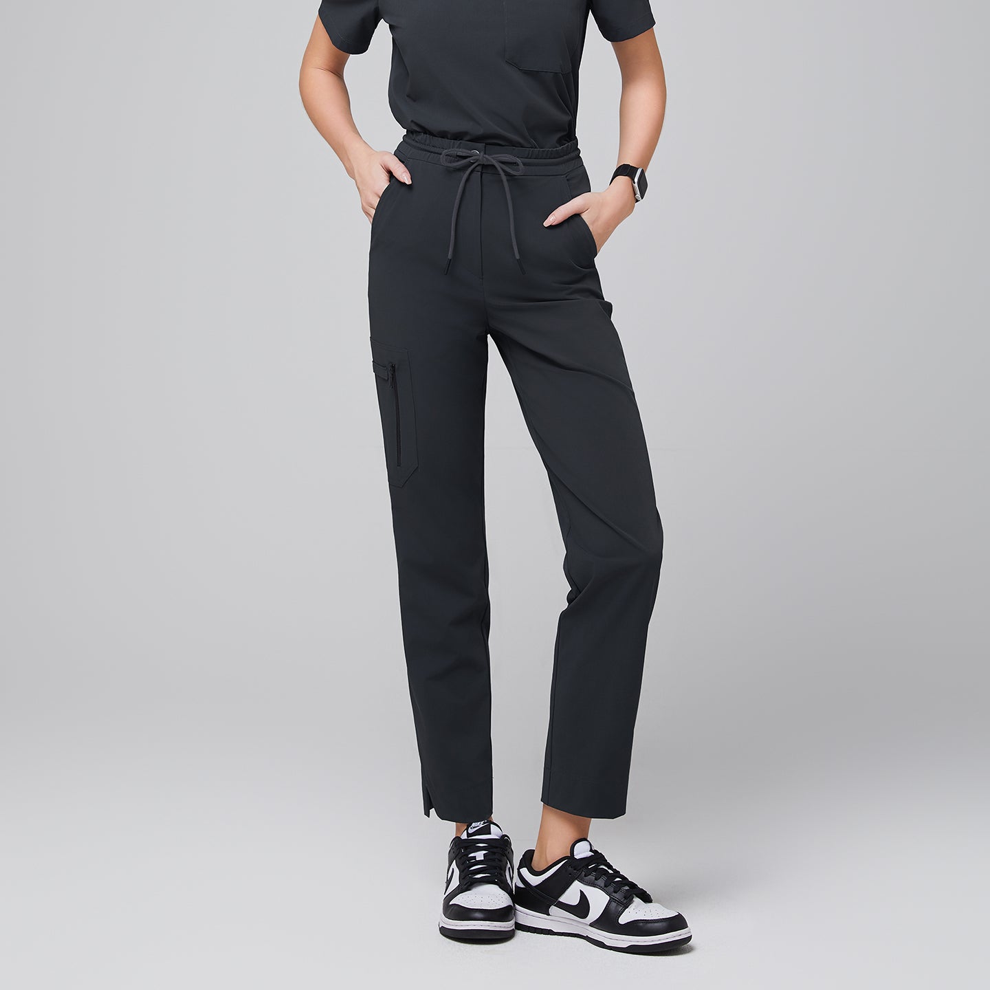 Image of Scrub pants with a drawstring waist, zipper pockets, and split hem, designed for comfort and functionality, paired with sneakers for a modern look,Deep Gray