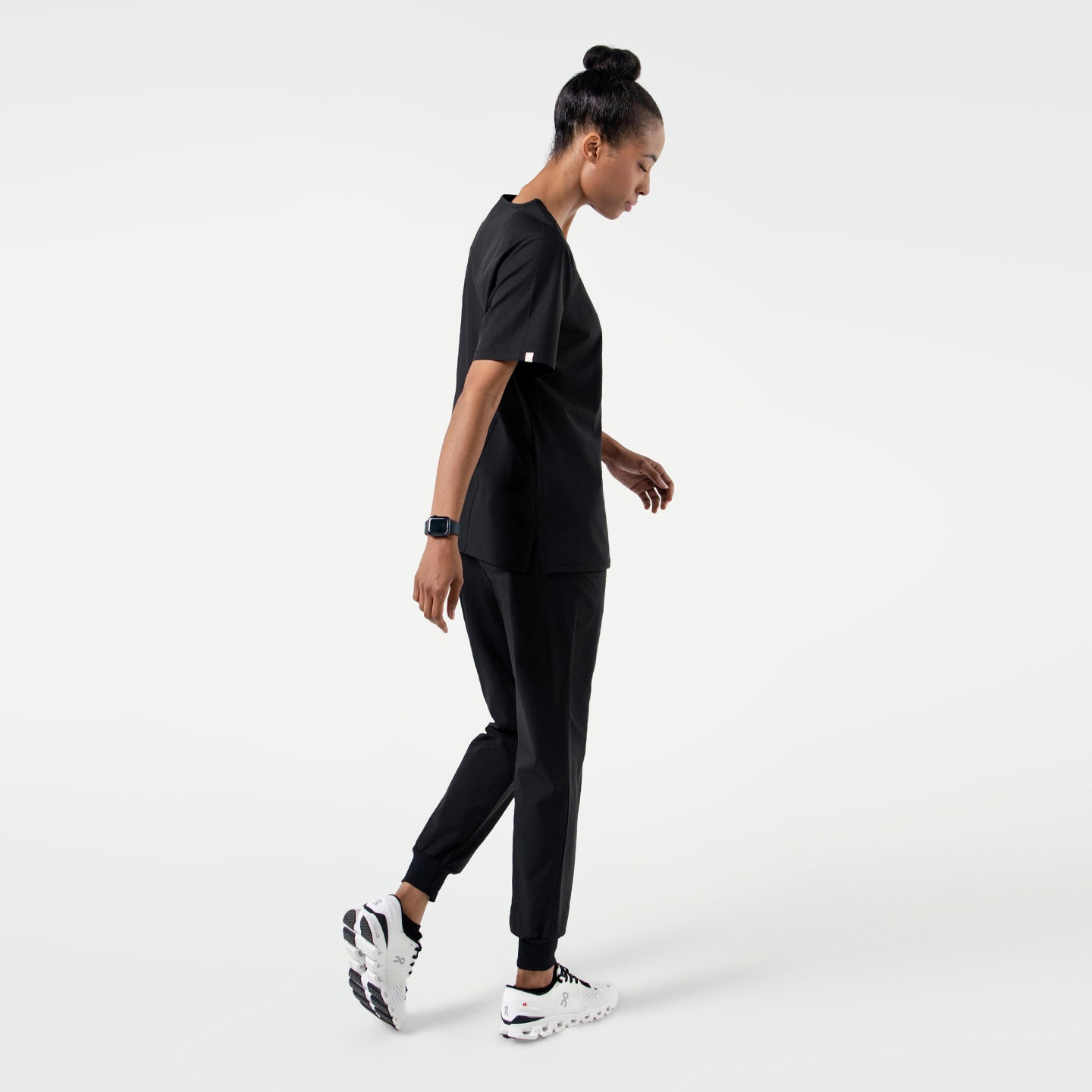 Image of Model wearing Eco Black 3 Pocket Scrub Top, shown from the side while walking.