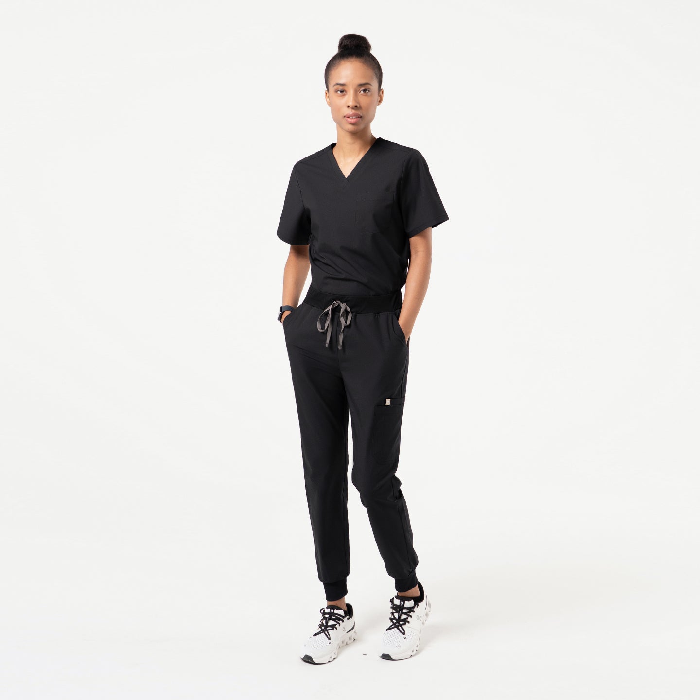 Image of A healthcare professional in a Pine Green V-neck scrub top with a three-pocket design, shown in a side profile while holding a stethoscope.