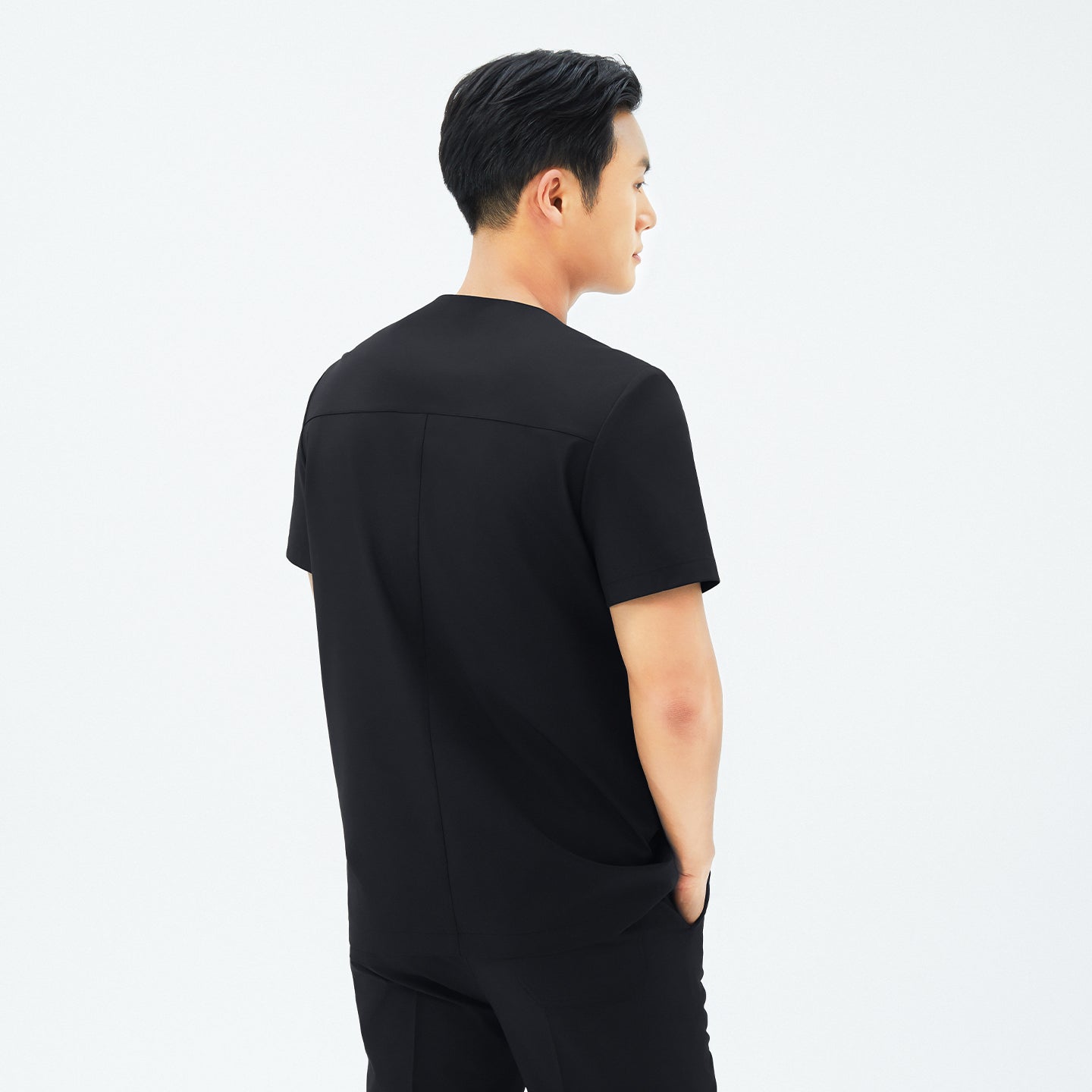 Image of Back view of TUL DS-187 Men's Round Snap Zipper Scrub Top in Eco Black, emphasizing structured seams and a comfortable silhouette.