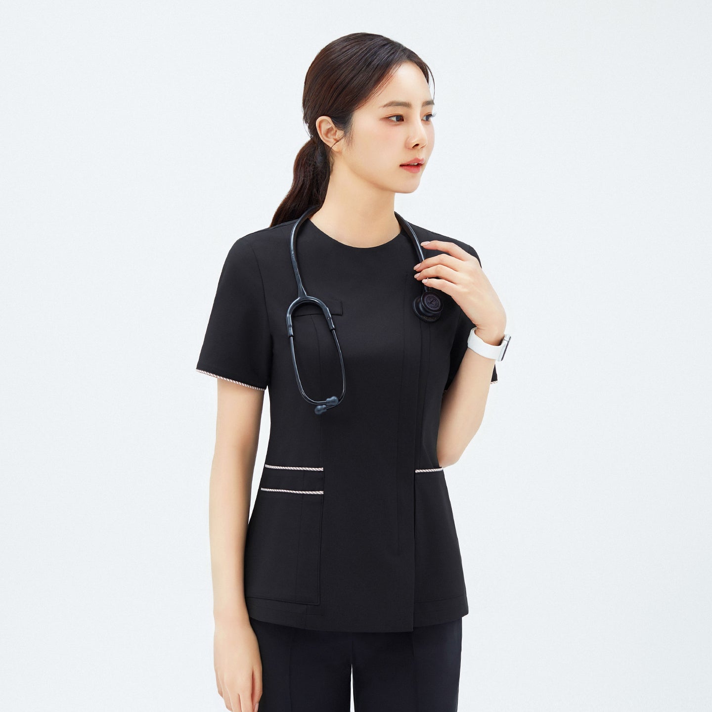 Close-up of TUL OS-206 Eco Black scrub top with contrasting edge stripes on sleeves and waist, worn by a medical professional.