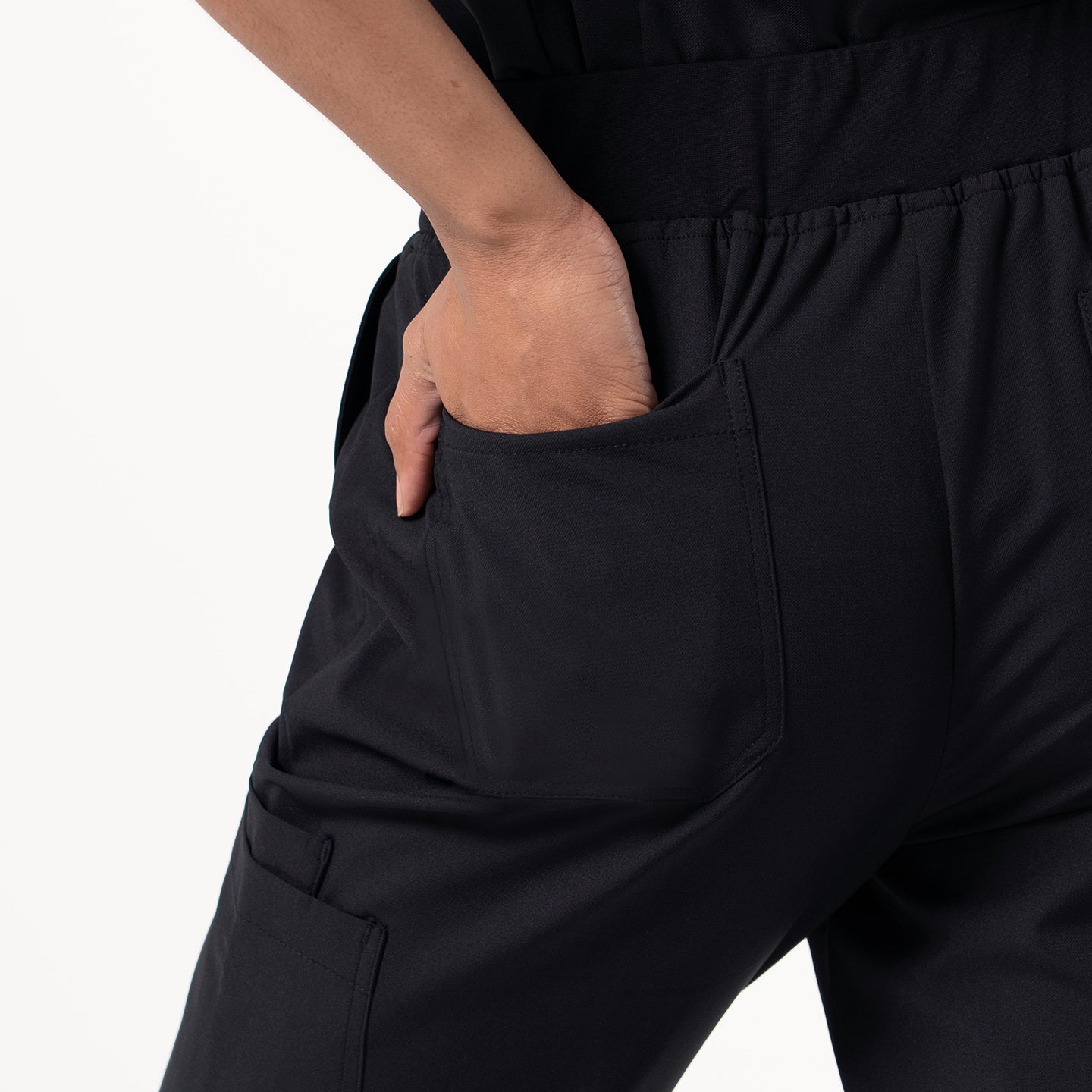 Eco Black Pocket Jogger Scrub Pants shown from the back, highlighting the relaxed waistband and spacious rear pocket with a hand placed inside.