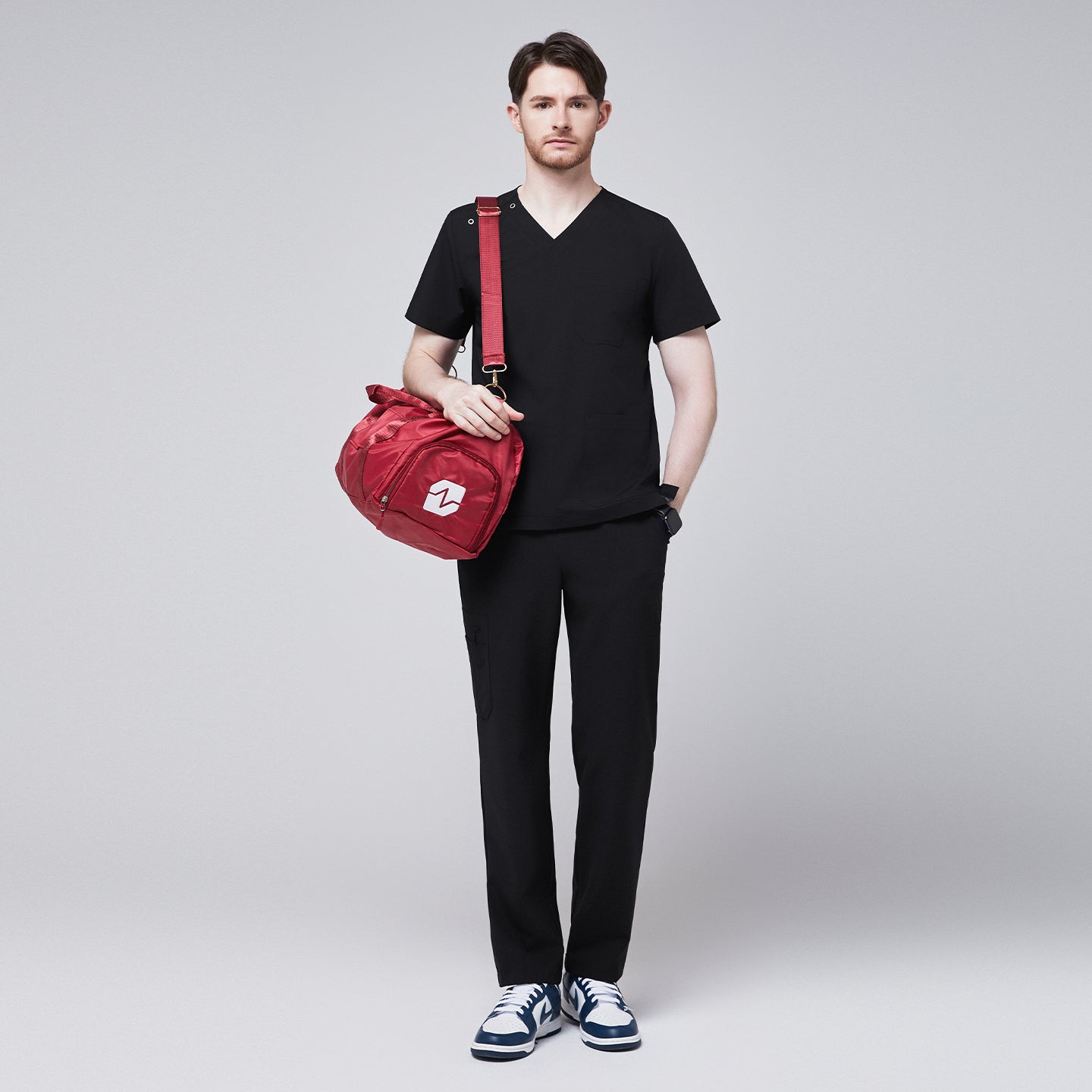 Image of Man wearing Zenir black shoulder button scrub top with chest and lower pockets, featuring a red pen in the chest pocket,Eco Black