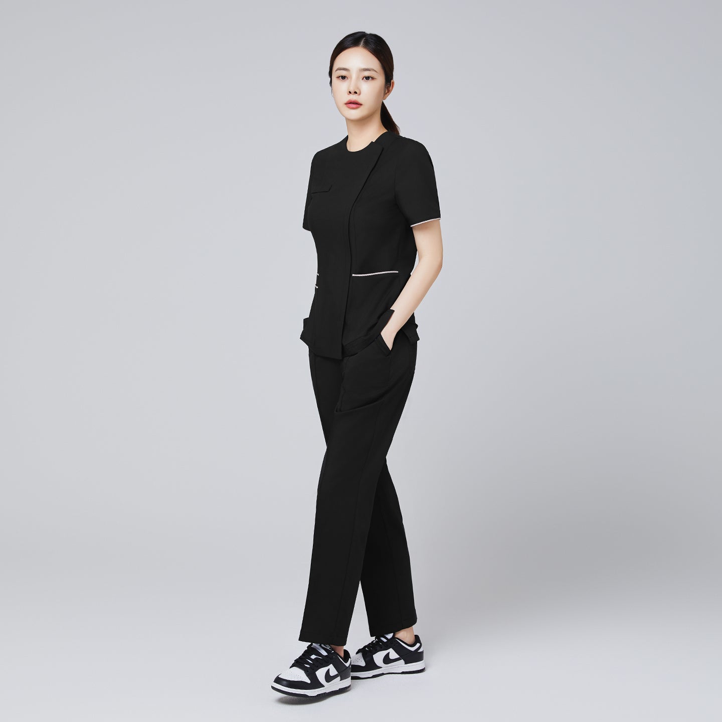 Full-length shot of TUL Women's Premium Banding Pants in Eco Black, paired with a matching scrub top for a cohesive uniform.