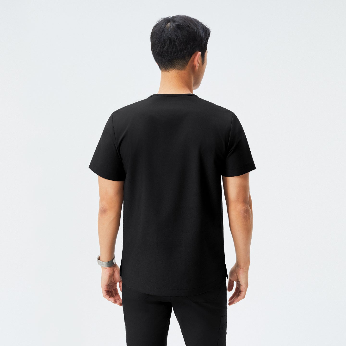 Man wearing black scrubs with short sleeves and matching pants, facing away from the camera,Eco Black