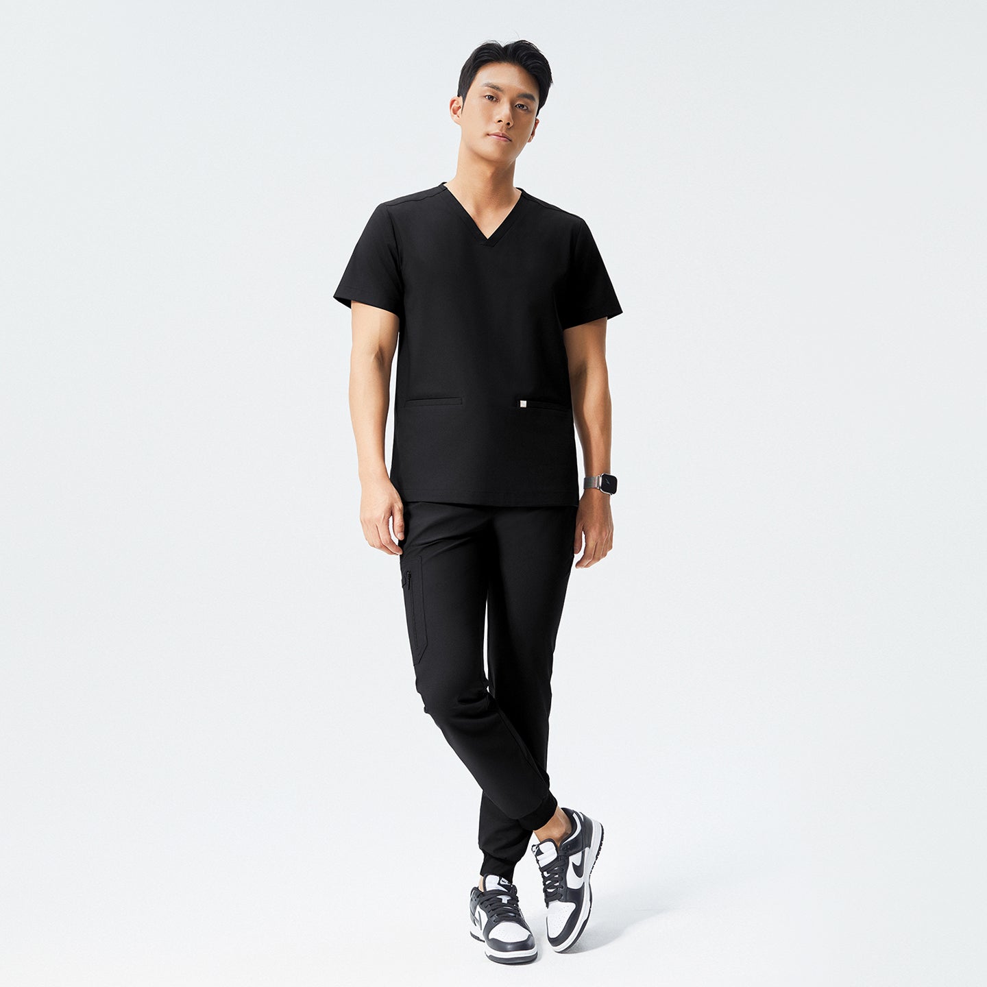 Man wearing eco black scrubs with a V-neck top and jogger-style pants, paired with black sneakers,Eco Black